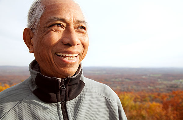 older man smiling in the sun out in nature