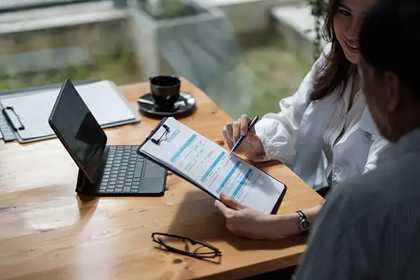 dentist helping her patient fill out insurance paperwork on a clipboard