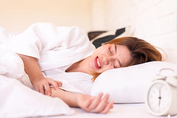 Stressed woman unconsciously grinding her teeth while sleeping on the bed.