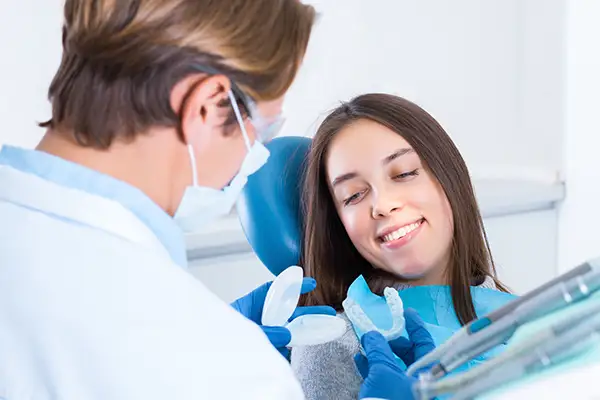 Dentist presenting mouth guard options to a smiling patient during a dental consultation.